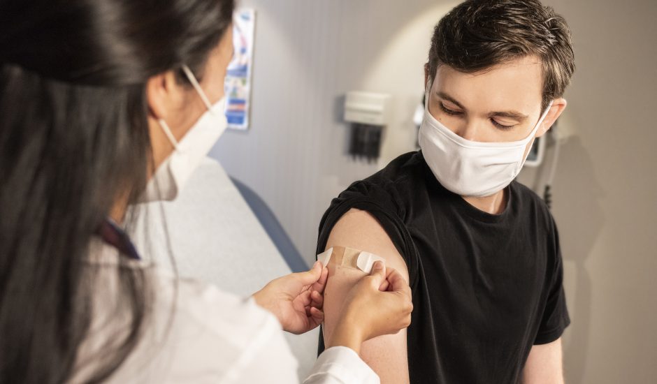 Une infirmière met un pansement sur le bras d'un homme après un vaccin.