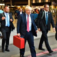 Boris Johnson en train de marcher avec une malette rouge à la main