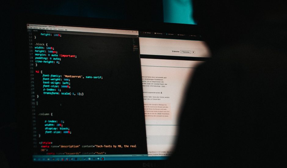 un homme dans le noir devant un écran d'ordinateur avec ligne de code