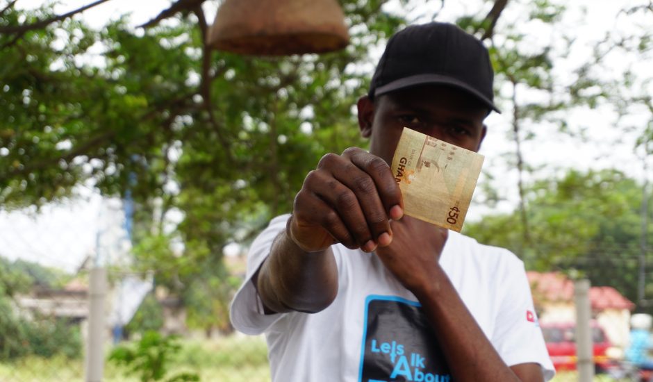 Un homme tenant 50 cedis, la monnaie officielle du Ghana dont une MNBC va sortir.