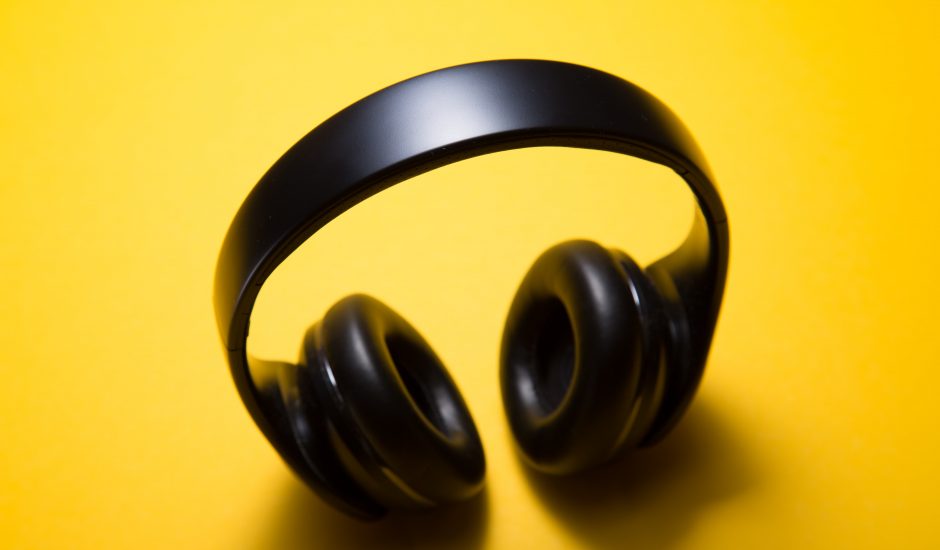 Un casque audio bluetooth noir, pris sur un fond jaune