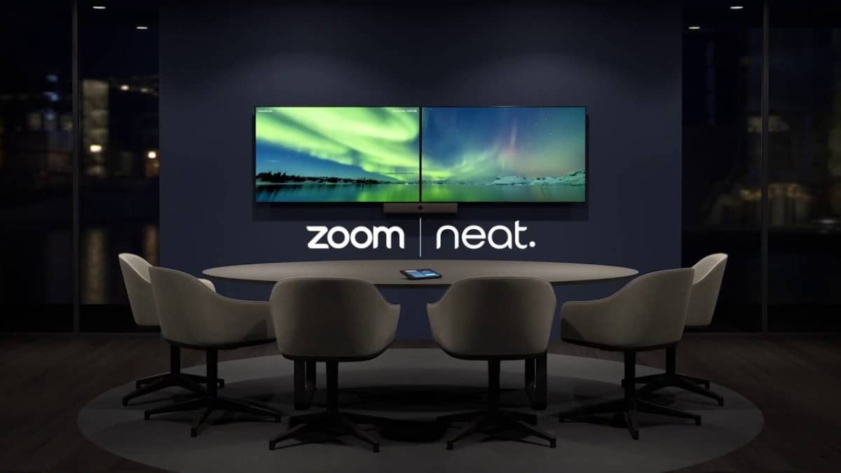 Les logos de Zoom et Neat sous deux écrans dans une salle de réunion