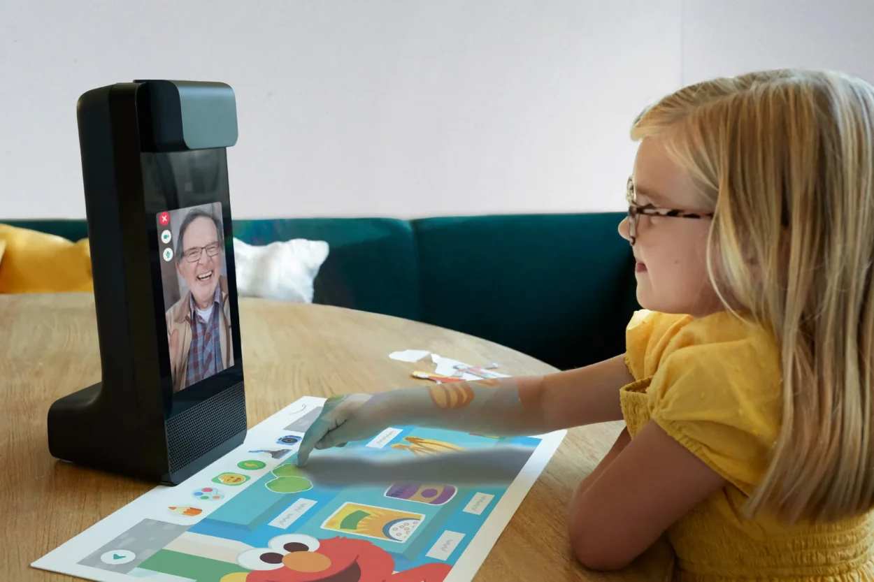 Une petite fille qui joue à distance avec son grand-père à un jeu diffusé sur le projecteur intégré à l'appareil de visioconférence Echo Glow