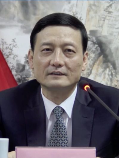 Xiao Yaqing devant un pupitre avec drapeau de la Chine en fond