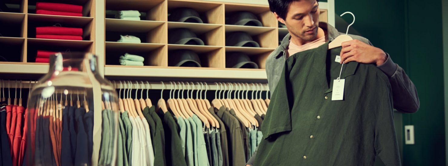 un homme dans un magasin de vêtements avec une chemise verte dans les mains