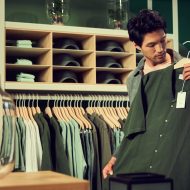 un homme dans un magasin de vêtements avec une chemise verte dans les mains