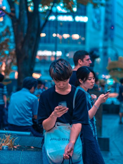 Dans la rue, des Japonais sont sur leur smartphone.