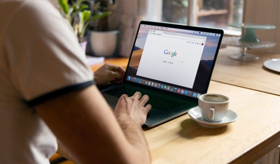 Un homme sur un ordinateur avec une tasse et Google