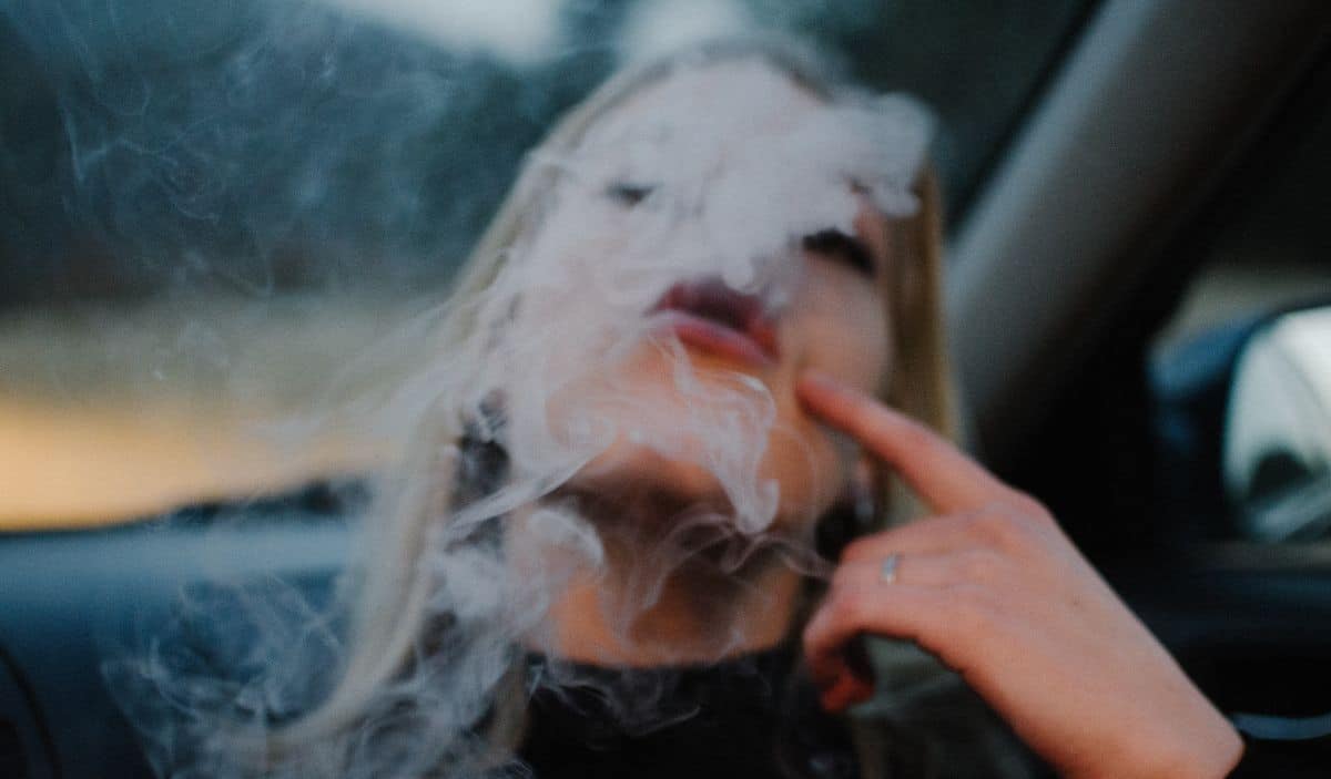 une jeune femme qui expire de la fumée
