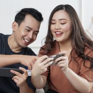 Deux personnes asiatiques rigolent devant un smartphone.