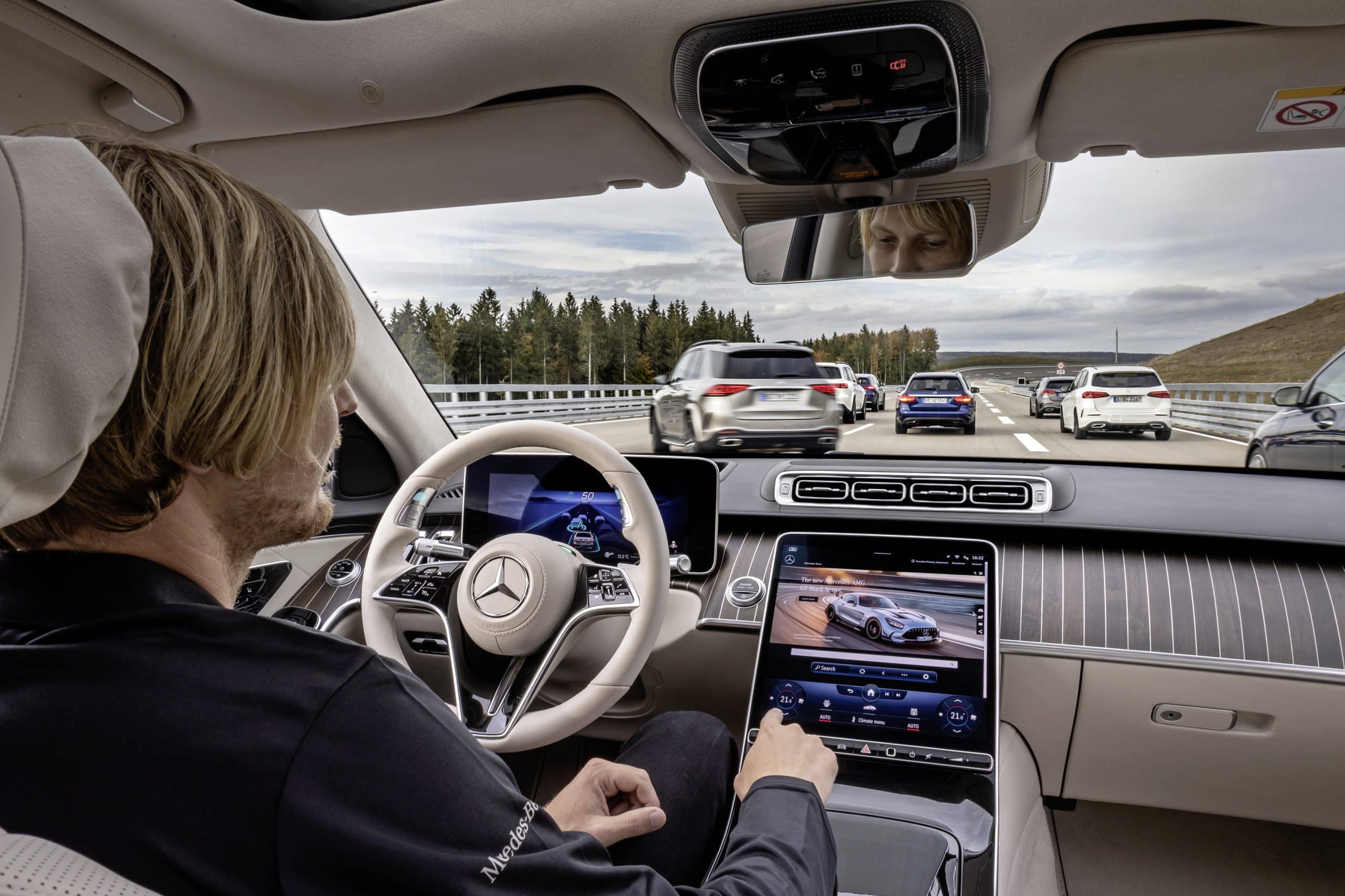 un conducteur dans l'habitacle d'une voiture active la conduite autonome sur route avec d'autres véhicules.