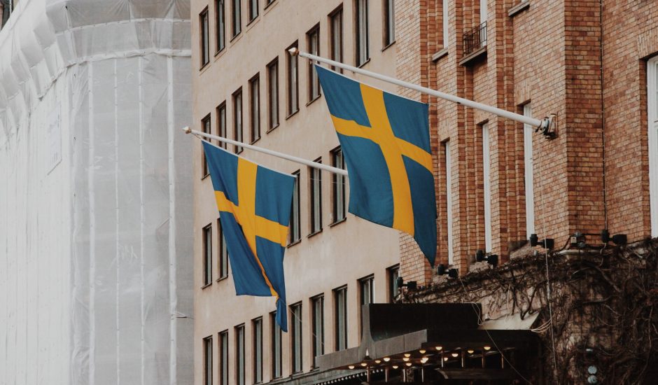 Photographie de deux drapeaux suédois sur un bâtiment.