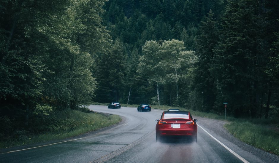 Un véhicule Tesla roule sur une route mouillée.