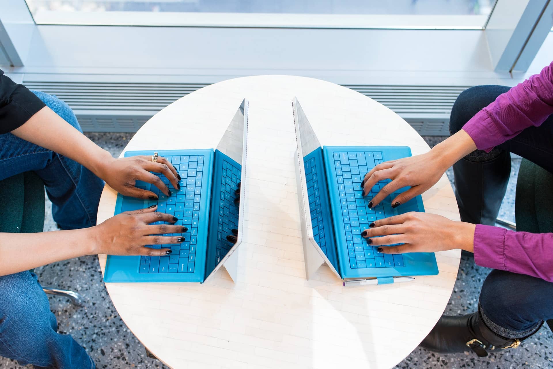 deux personnes face à face sur des ordinateurs portables bleus