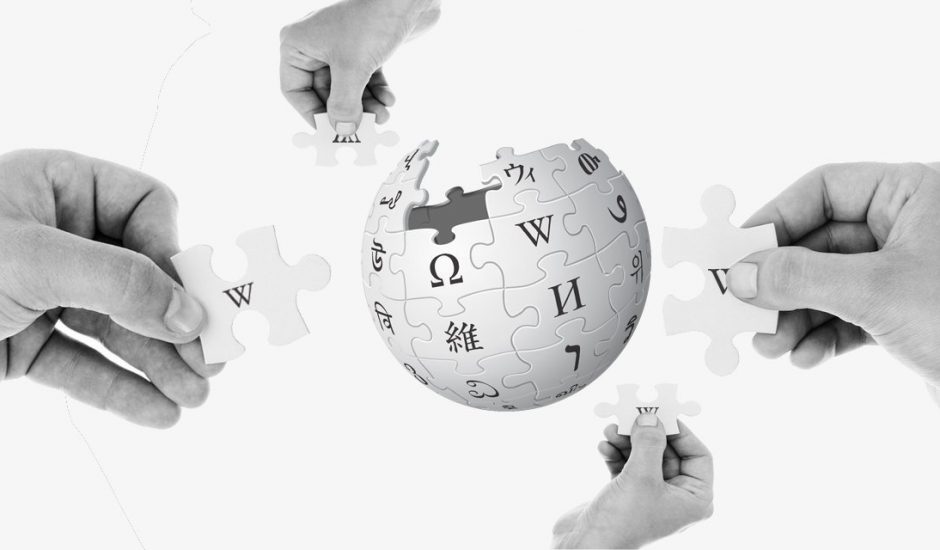 Logo de Wikipédia avec 4 mains autour.