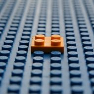 Orange LEGO brick placed on a large empty LEGO board