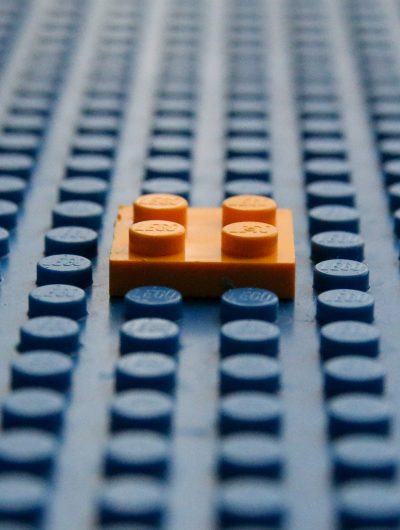 Une brique de LEGO orange posée sur une grande plaque LEGO vierge