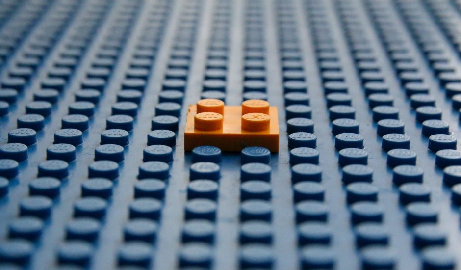 Une brique de LEGO orange posée sur une grande plaque LEGO vierge