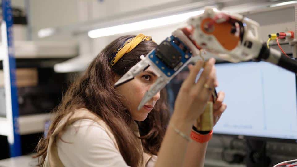 Ingénieure travaillant sur un bras robot.