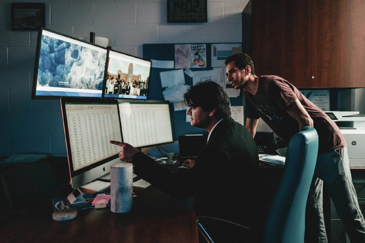 Deux personnes travaillant devant plusieurs écran d'ordinateur