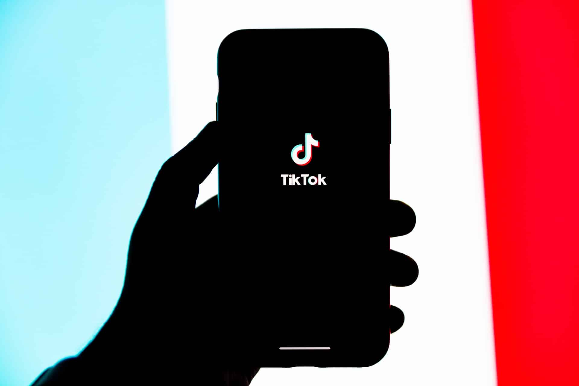 une personne tenant un téléphone avec le logo tiktok