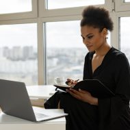 une femme prenant des notes devant un ordinateur portable