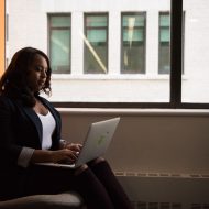 une femme assise avec un ordinateur portable sur ses genoux