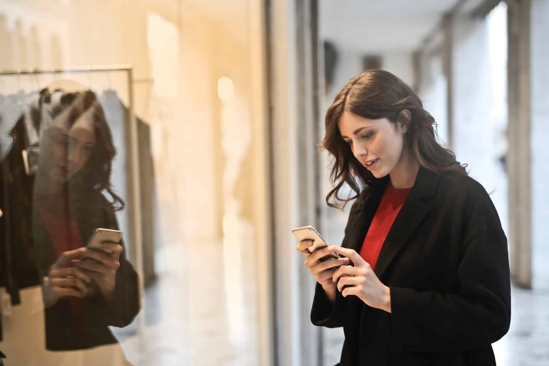 une femme en manteau noir sur son smartphone