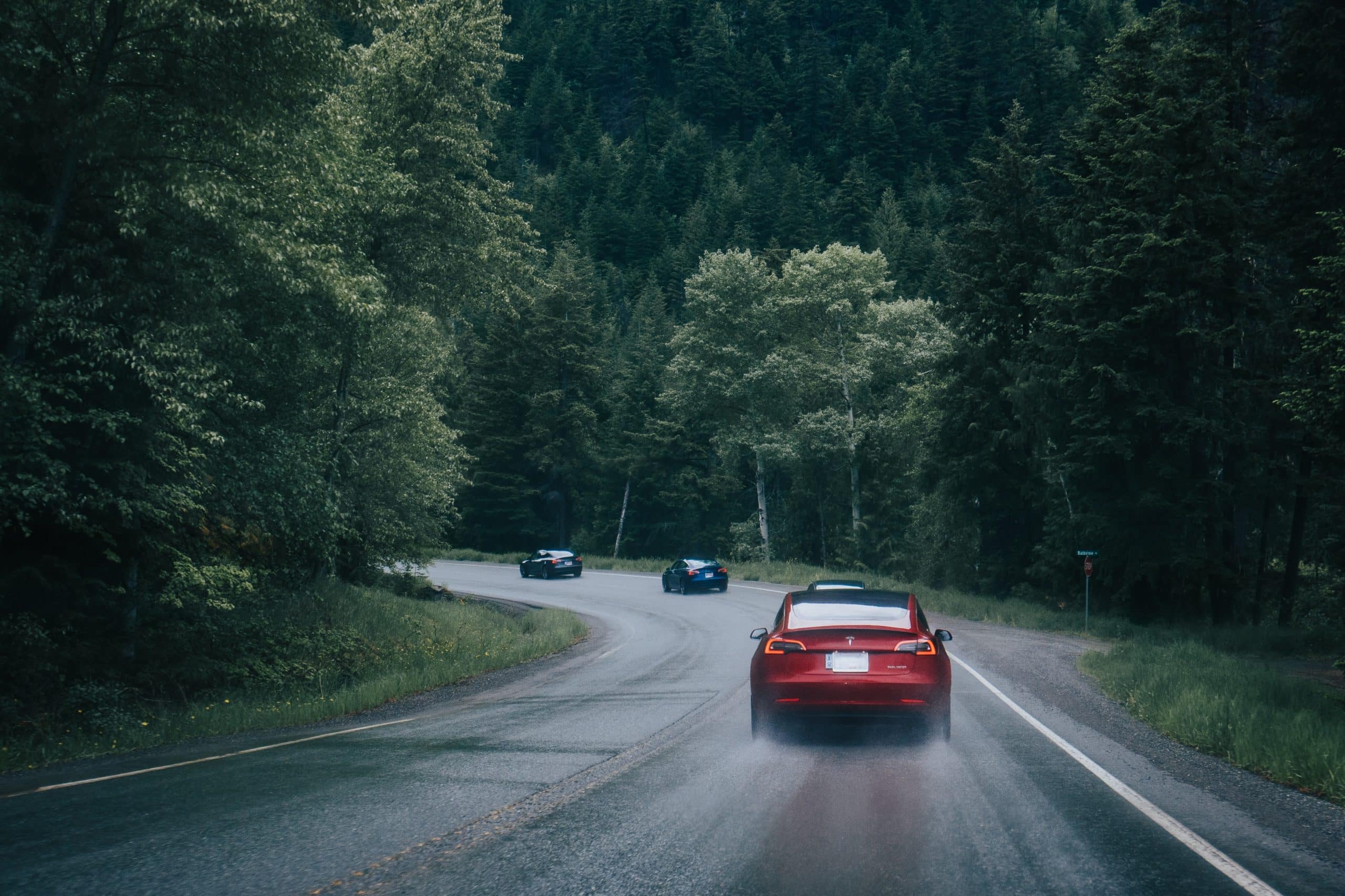 Un véhicule Tesla roule sur une route mouillée.