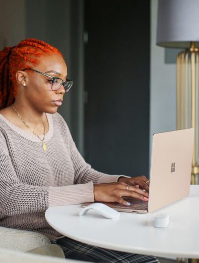 une femme aux cheveux rouges devant un ordinateur portable surface