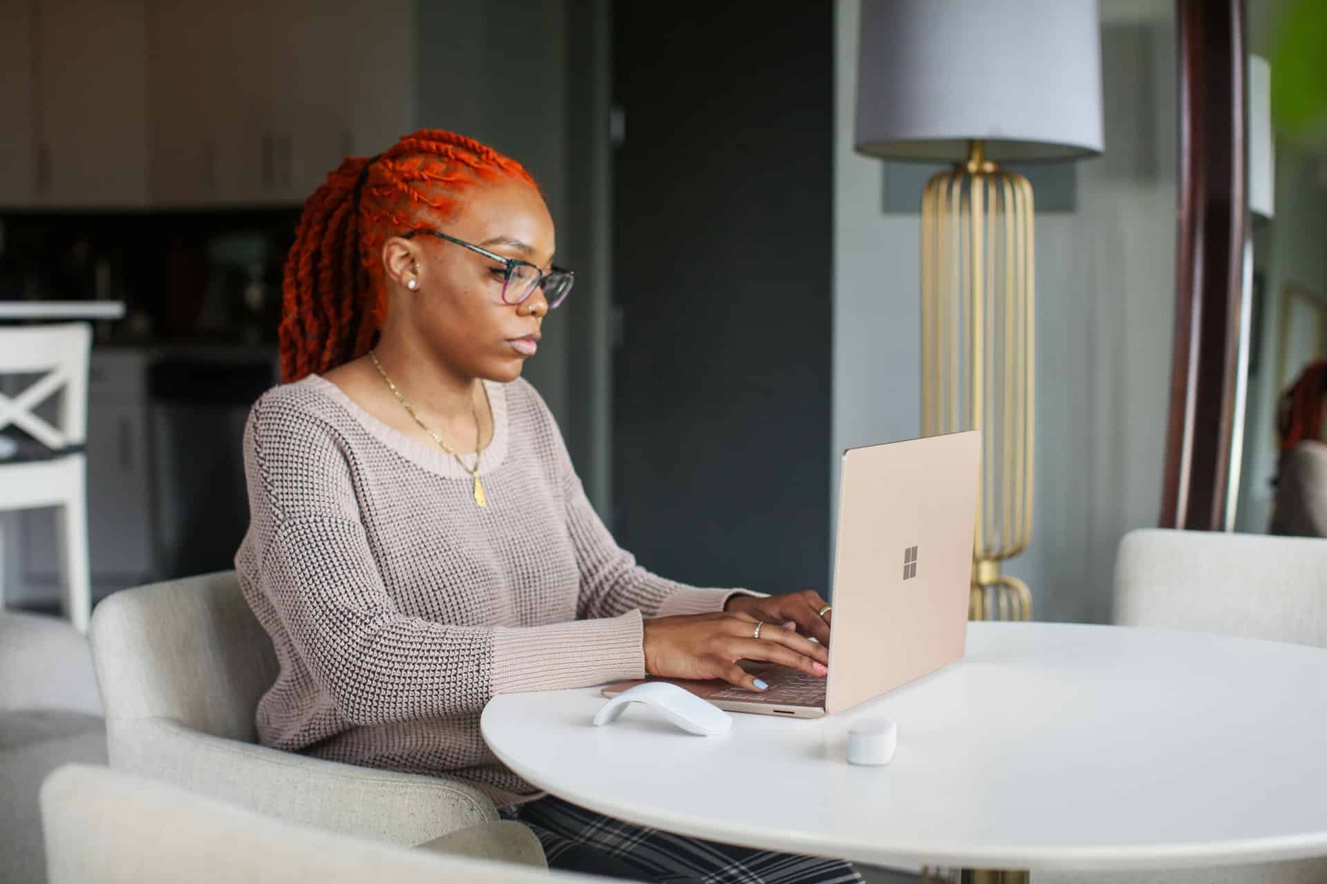 une femme aux cheveux rouges devant un ordinateur portable surface