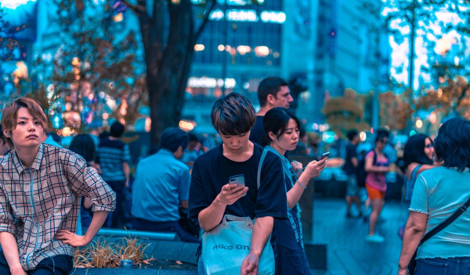 Dans la rue, des Japonais sont sur leur smartphone.