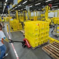 Une employée d'Amazon tire une charge lourde dans un entrepôt.