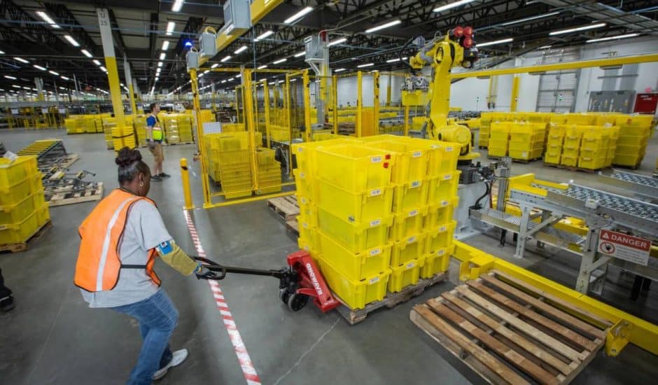 Une employée d'Amazon tire une charge lourde dans un entrepôt.
