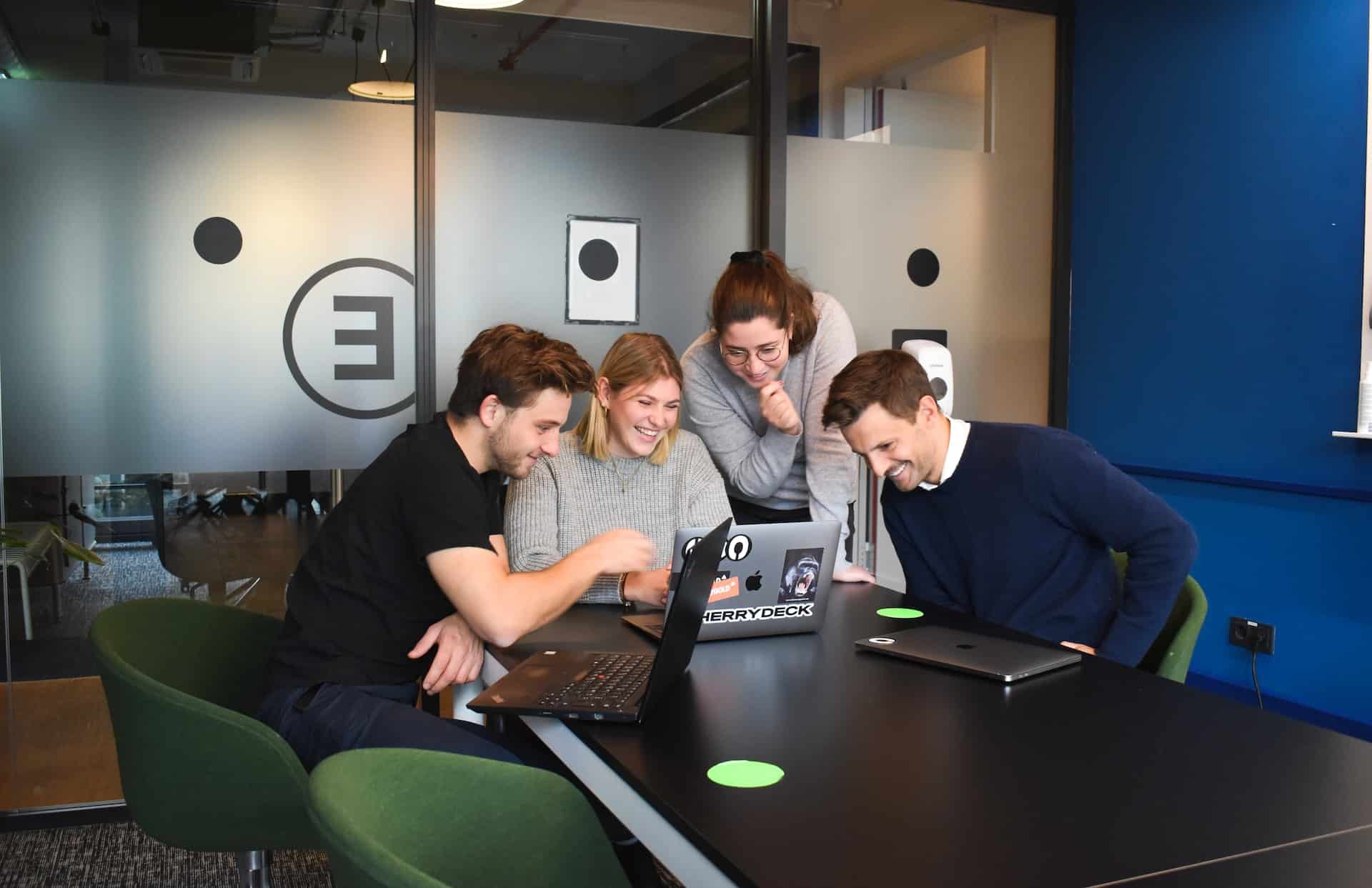 une équipe de deux hommes et deux femmes dans un bureau, tous autour d'un ordinateur portable