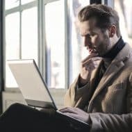 un homme pensif avec un ordinateur portable sur les genoux