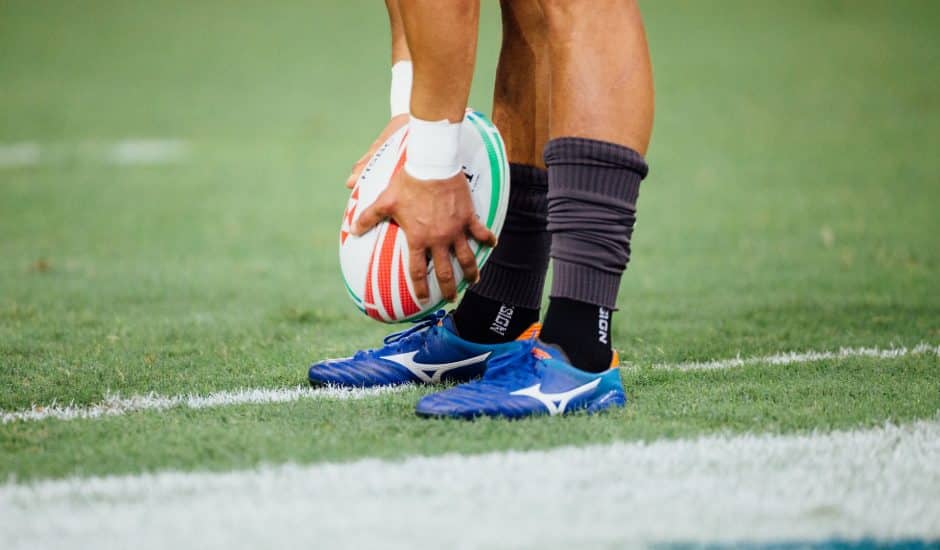 un rugbyman avec un ballon tenu près de ses pieds