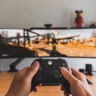 Joueur tenant une manette d'Xbox et jouant à un jeu vidéo sur son téléviseur.