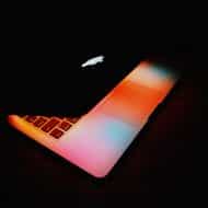 Un Apple MacBook Pro d'ancienne génération dans une pièce sombre.