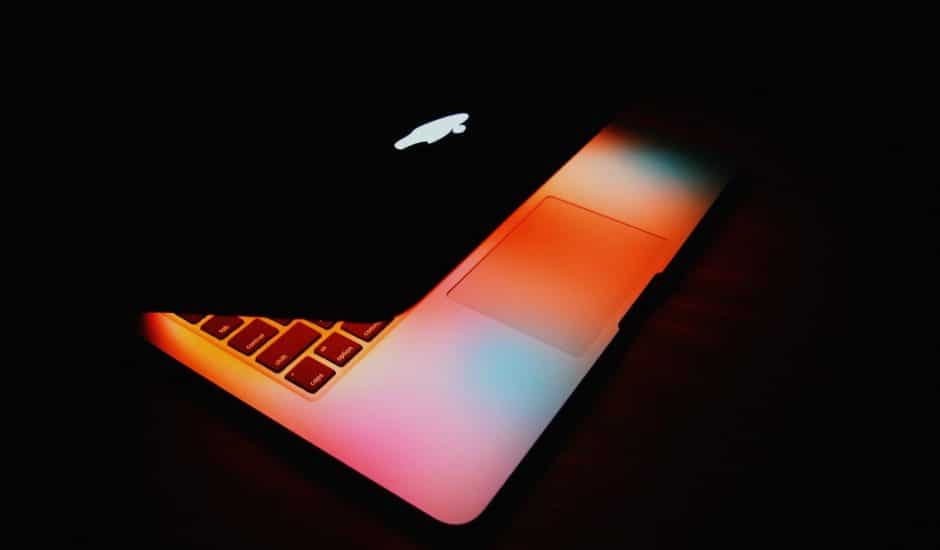 Un Apple MacBook Pro d'ancienne génération dans une pièce sombre.