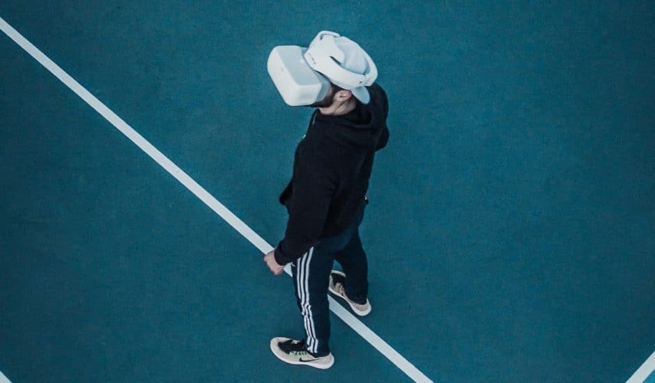 Un homme sur un court de tennis, portant un casque de réalité virtuelle.