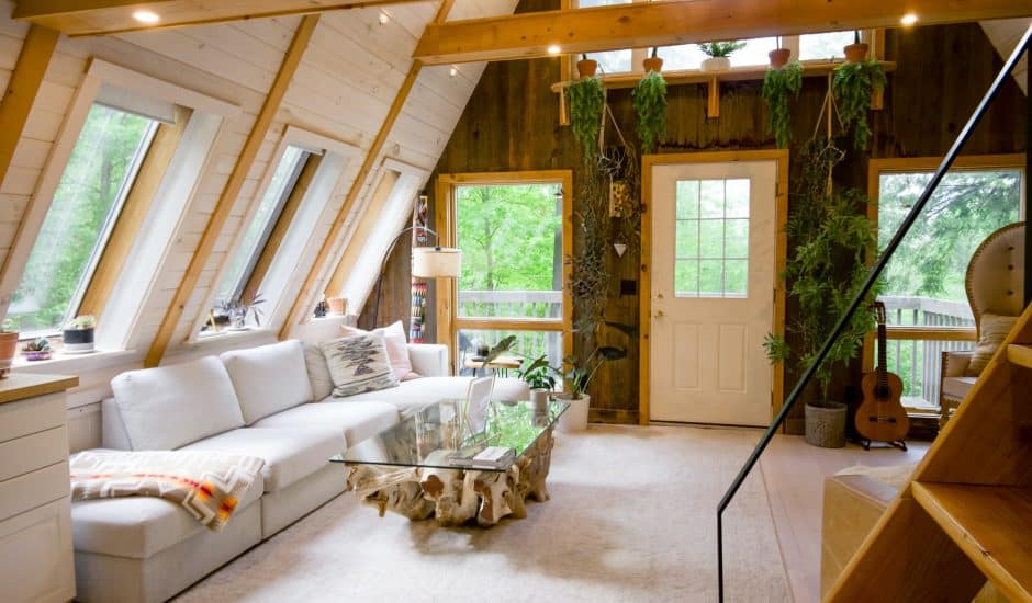 Un appartement avec des poutres en bois, un canapé blanc et de la végétation murale.
