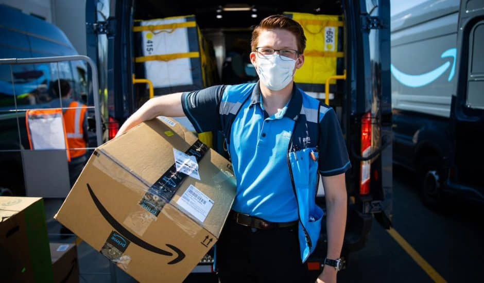 un livreur de la société Amazon avec un uniforme, portant un colis