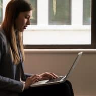une femme de profil avec un ordinateur sur les genoux