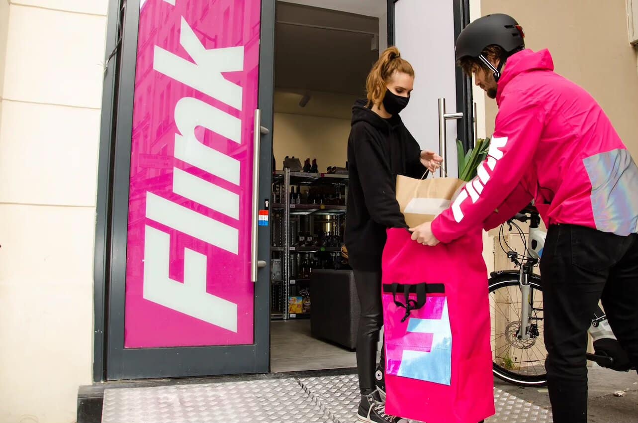 Un livreur Flink qui prépare son sac de courses avec une employée