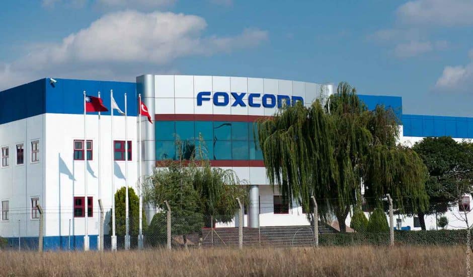 Photographie d'un bâtiment Foxconn en Chine placé devant un champs avec des arbres
