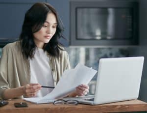 une femme avec des documents devant son ordinateur