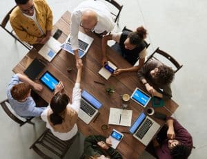 vue de haut d'une équipe en réunion autour d'une table avec des ordinateurs, deux personnes se serrent la main