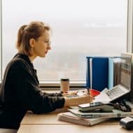 une femme devant son ordinateur, un TPE et une calculatrice à côté d'elle