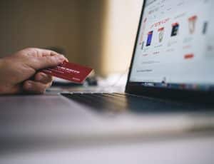 une main tenant une carte bancaire devant un ordinateur avec une boutique en ligne ouverte